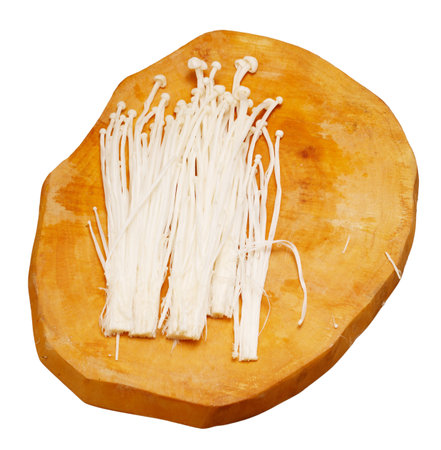 Enoki mushrooms on a wooden board isolated on white background.