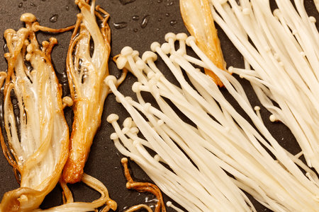 Enoki mushrooms are fried in a pan.の写真素材