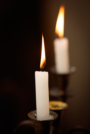 Two candles are lit and are on a table. One of the candles is taller than the otherの写真素材