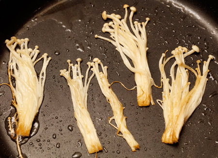 Enoki mushrooms are fried in a pan.の写真素材