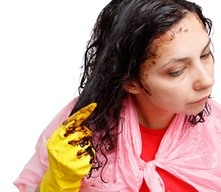 A woman applies dye to her hair with a hand in a yellow glove. Isolated on a white backgroundの写真素材
