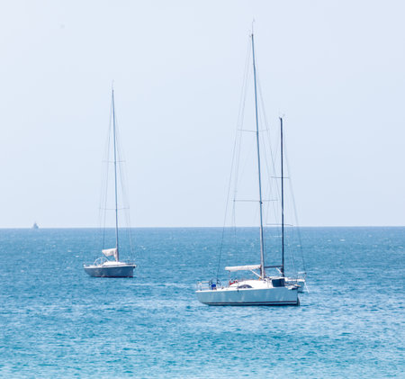Two sailboats are in the water. One is in the foreground and the other is in the background