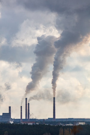 A large cloud of smoke is rising from a power plant. The smoke is thick and billowing, and it is clear that the plant is emitting a lot of pollutionの写真素材