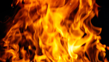 A close up of a large flame with a dark background. The flame is orange and yellow, and it is very hot.の写真素材