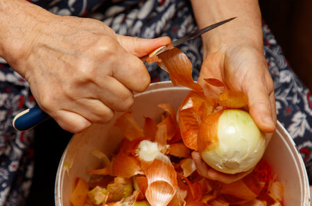 A person is cutting an onion with a knife. The onion is in a bowl. The person is wearing a blue shirtの写真素材