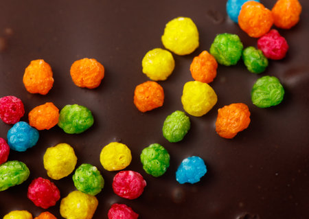 A chocolate bar with colorful cereal pieces on top. The cereal pieces are in various colors including green, yellow, and blueの写真素材