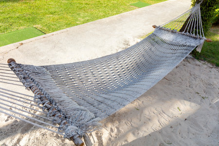 A white rope hammock is on the ground. The hammock is made of a white materialの写真素材
