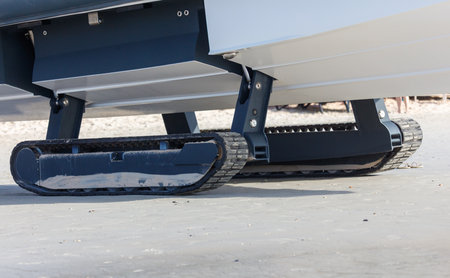 A boat on tracks moves along the beach.