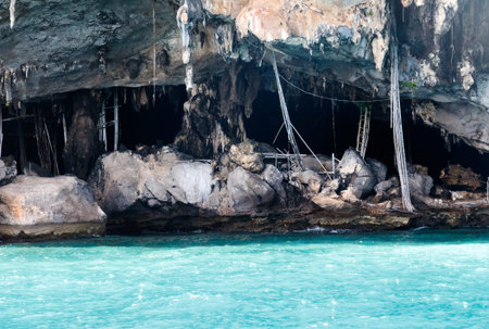 A cave with a ladder hanging from the ceiling. The cave is dark and has a lot of rocks