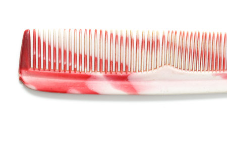 A red and white comb with white bristles. The comb is made of plasticの写真素材