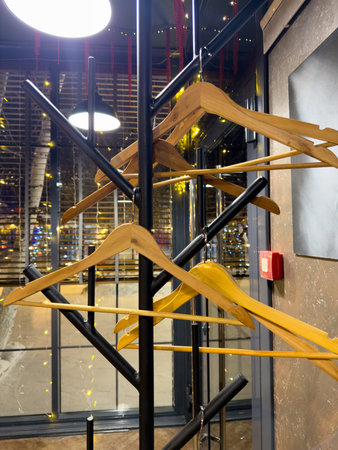 A rack of clothes is hanging on a wall. The rack is made of wood and has a black base