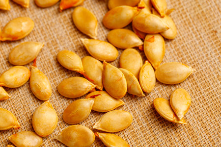 A bunch of pumpkin seeds are spread out on a table. They are all different sizes and shapesの写真素材