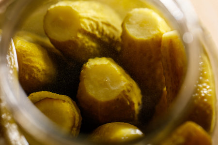 A jar of pickles with a lid on top. The pickles are yellow and have a green stem