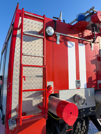 A ladder is attached to the side of a red fire truck. The ladder is silver and has a red top