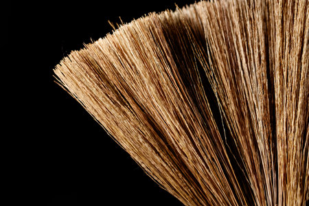 A brush with brown bristles. The brush is on a black background. The brush is long and thin