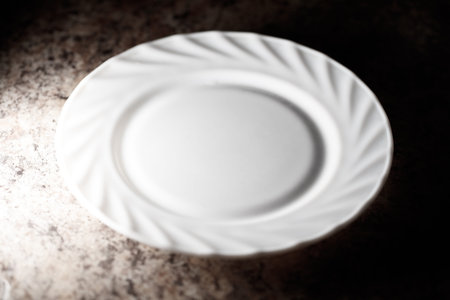 A white plate with a ruffled edge. It is sitting on a counter. The plate is not full