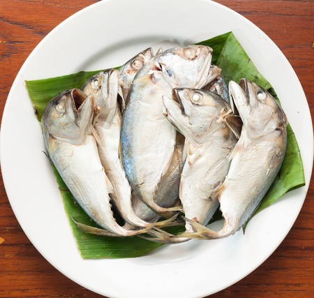 boiled mackerel on green banana leaf and white dishの写真素材