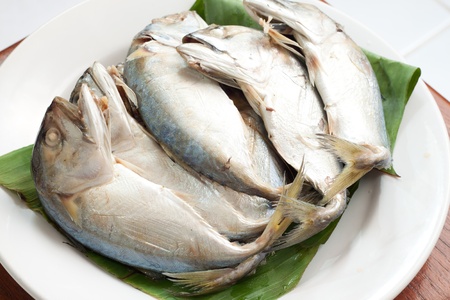 boiled mackerel on green banana leaf and white dishの写真素材
