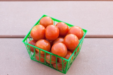 Fresh tomatoes in green plastic basketの写真素材