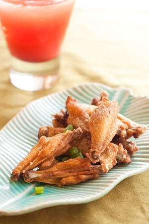 Thai style fried chicken wings on green table with red cold drinkの写真素材