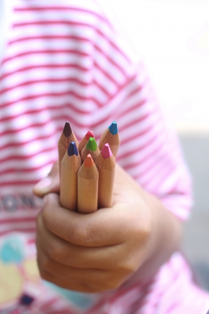 A child hold color pencils with a little handの写真素材
