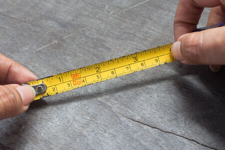 Woman's hands holding tape measure on wood backgroundの写真素材