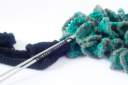 Piece of black knitting on knitting needles with finished knitting scarfの写真素材