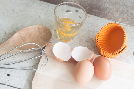 ingredients and tools to make a cake, eggs, bakery cups on wood tableの写真素材