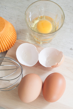 ingredients and tools to make a cake, eggs, bakery cups on wood tableの写真素材