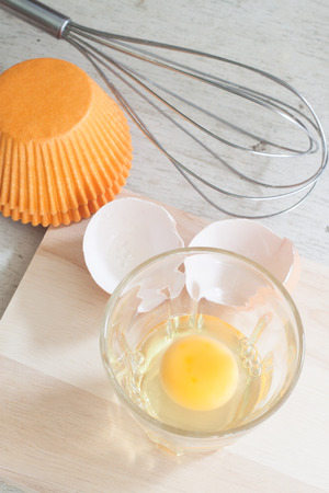 ingredients and tools to make a cake, eggs, bakery cups on wood tableの写真素材