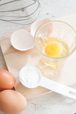 ingredients and tools to make a cake, eggs, bakery cups on wood tableの写真素材