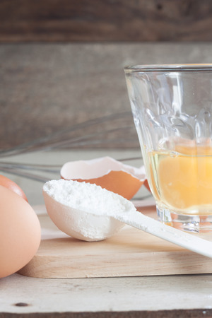 ingredients and tools to make a cake, eggs, bakery cups on wood tableの写真素材