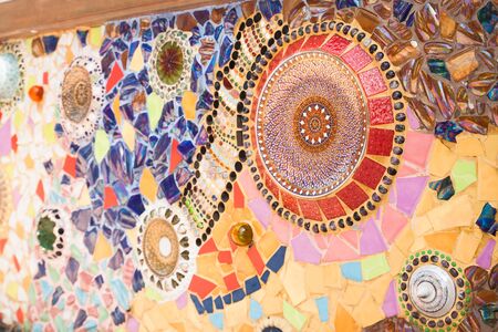 Colorful plates and ornate pottery lids used as part of tile mosaic on a wall at Wat Pha Son Kaew temple in Petchaboon province in Thailandの写真素材