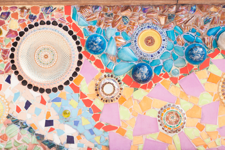 Colorful plates and ornate pottery lids used as part of tile mosaic on a wall at Wat Pha Son Kaew temple in Petchaboon province in Thailandの写真素材
