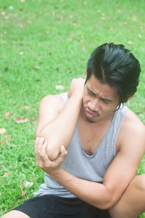 Asian man elbow pain in nature, grasses backgroundの写真素材