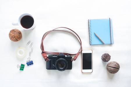 Top view of working elements with film camera, smartphone and a cup of coffee on white background