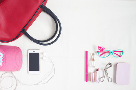 Overhead view of essential beauty items, Top view of smartphone, red hand bag, fashion eyeglasses and cosmeticの写真素材