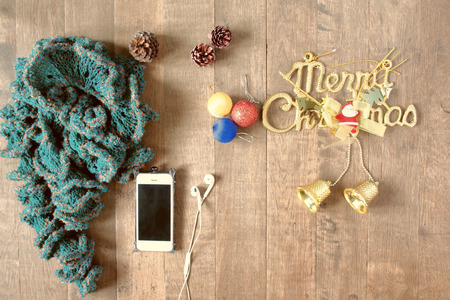 Flat lay of winter scarf, Christmas decoration items and smartphone on wooden background, XMAS,...