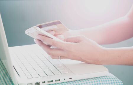 Hands holding smartphone, credit card and using laptop. Online shoppingの写真素材