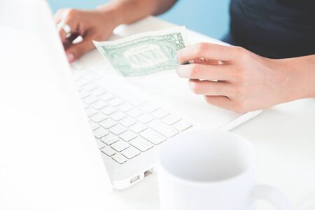 Hand holding dollar and using laptopの写真素材