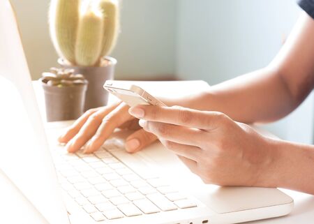 Hands holding smartphone and using laptop. Online shoppingの写真素材