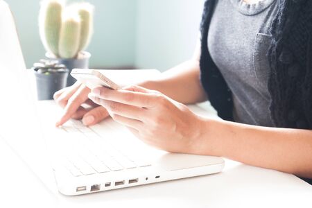 Hands holding smartphone and using laptop. Online shoppingの写真素材
