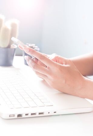 Hands holding smartphone and using laptop. Online shoppingの写真素材