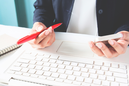 Business woman holding mobile phone and using laptopの写真素材