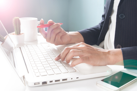 Business woman holding mobile phone and using laptopの写真素材