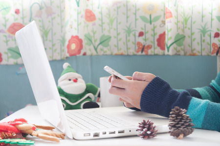 Hands holding mobile phone, credit card and using laptop with Christmas decoration, Shopping onlineの写真素材