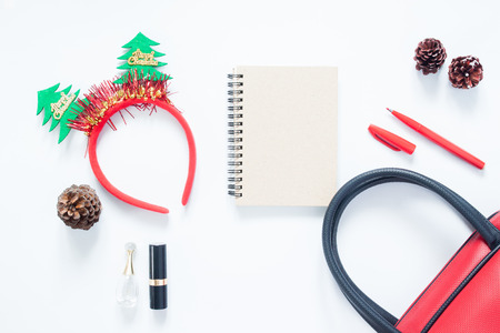 Christmas composition. Christmas fashion for girl, cosmetics, bag, pine cones, notebook and red pen with copy space. Flat lay, top viewの写真素材