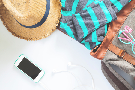 Flat lay female clothes and accessories collage with t-shirt, fashion glasses, hat,  with mobile phone and earphone on white background.の写真素材