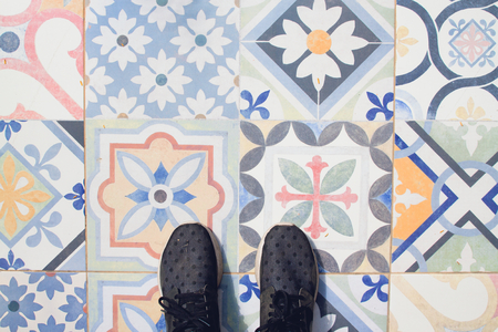 Selfie of feet with sneaker shoes on vintage art pattern tiles floor, top viewの写真素材