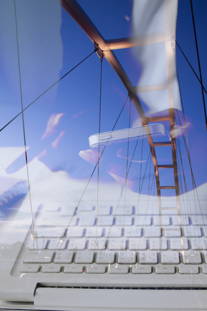 Business woman holding mobile phone and using laptop with modern design bridgeの写真素材